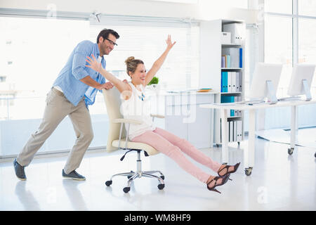 Sorridendo gli editor di foto per divertirsi su una sedia girevole in office Foto Stock