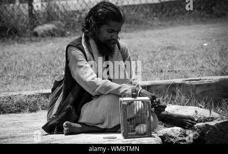 Un indovino sadhu in India con il suo pappagallo. Foto in bianco e nero. Foto Stock