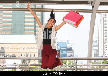 Ritratto di sorridente giovane donna con le borse della spesa il salto nel ponte di coperta