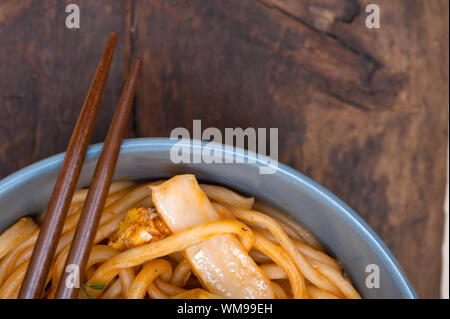 Tirata a mano tesa cinese di spaghetti ramen su una ciotola con baguette Foto Stock