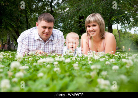I giovani della famiglia nel parco, giace su un'erba e sorrisi Foto Stock