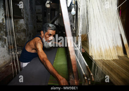 Un tessitore di seta lavora in una piccola fabbrica di Varanasi (India). Foto Stock