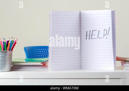 Aiutare a segno. Aprire il notebook con la parola scritta su Help desk con pila libri e quaderni Foto Stock