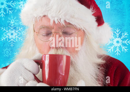 Santa drink da un bicchiere di rosso contro blu fiocco di neve pattern design Foto Stock