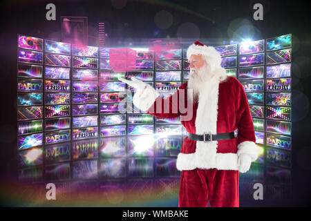 Santa mostra qualcosa alla telecamera contro lo schermo che mostra collage di immagini in discoteca Foto Stock
