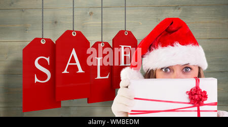 Festive bionda tenendo un dono contro imbianchiti doghe in legno sfondo Foto Stock