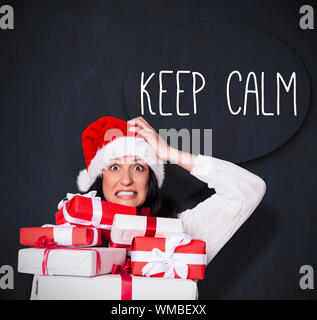 Scioccato donna con regali di Natale contro di Blackboard Foto Stock