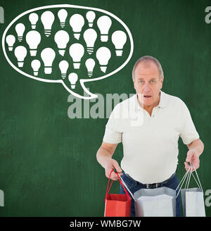 Scioccato uomo azienda shopping bags contro lavagna verde Foto Stock