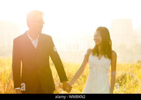 Sposa e lo Sposo Holding Hands, circondato da mattina naturale golden la luce del sole. Foto Stock