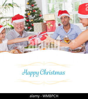 Immagine composita della madre dando figlia regalo di Natale contro il confine Foto Stock