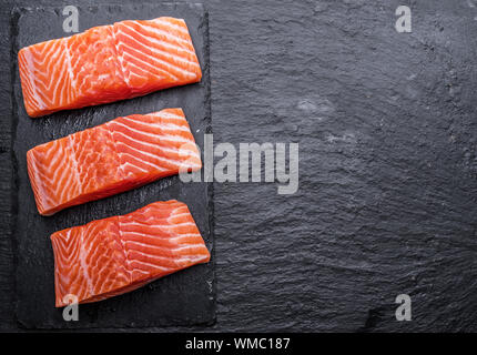 Fresco di filetti di salmone su nero tagliere. Vista dall'alto. Foto Stock