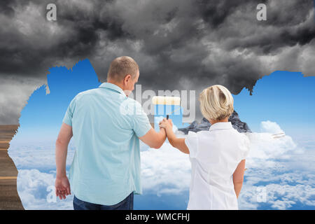 Immagine composita di felice coppia di anziani dipinto il cielo, da scuro a chiaro Foto Stock