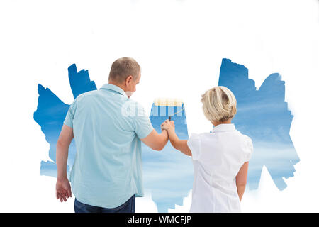 Immagine composita di felice coppia di anziani la verniciatura di un cielo sul muro bianco Foto Stock