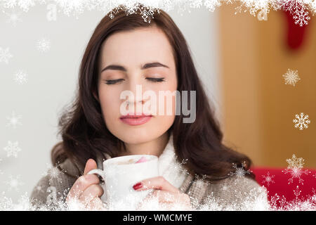 Brunette godendo di una cioccolata calda con marshmallow contro la foresta di abeti e i fiocchi di neve Foto Stock