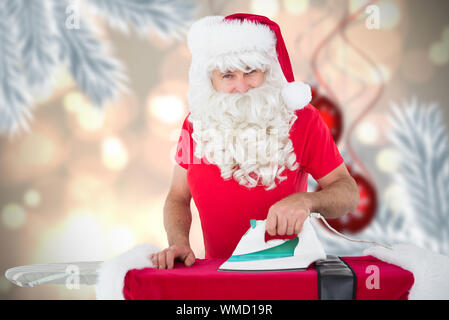 Felice santa claus a stirare la sua giacca contro il digitale appeso Pallina natale decorazione Foto Stock