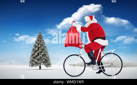 Santa ciclismo e tenendo il sacco contro abete nel paesaggio innevato Foto Stock