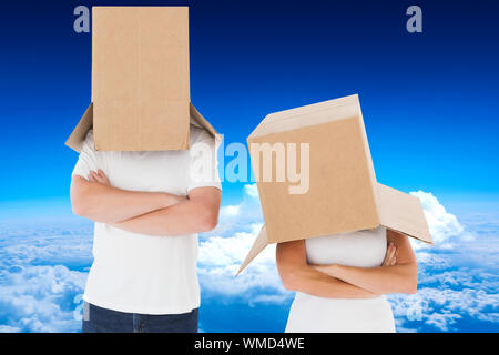 Coppia matura indossando le caselle sopra le loro teste contro il picco di montagna attraverso le nuvole Foto Stock