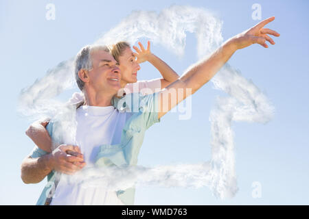 Felice l'uomo senior dando il suo partner un piggy back contro la sagoma della casa in nubi Foto Stock