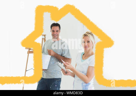 Coppia con campioni di colore e la scaletta in una nuova casa contro il contorno della casa Foto Stock