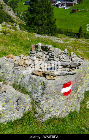 Pila di pietre e waymarker su roccia, montagne verdi e blu giornata di sole a Obergurgl, Ötztal, Austria, Foto Stock