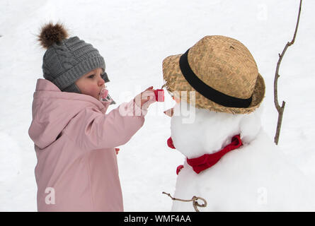 Bambina giocare nella neve e facendo un pupazzo di neve Foto Stock