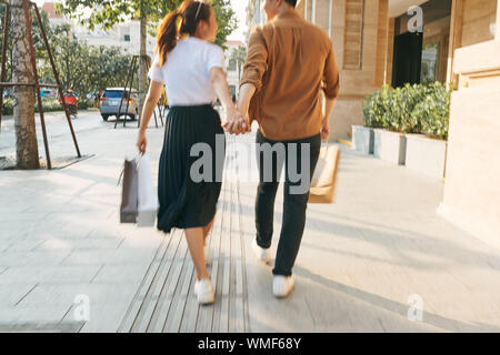 Abbassare la sezione corpo di un giovane turista giovane a piedi da store windows e tenendo la carta shopping bags in una città di destinazione. Foto Stock