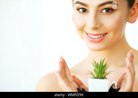 La cura della pelle. Donna con pelle chiara azienda verde Aloe Vera pianta. Trattamento di bellezza. La cosmetologia. Beauty Spa Salone Foto Stock