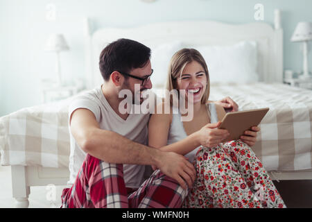 Giovane coppia attraente con tavoletta digitale in camera da letto Foto Stock