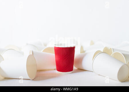 Carta rossa tazza di caffè si erge tra giacente white paper cups. Sfondo bianco, spazio di copia Foto Stock