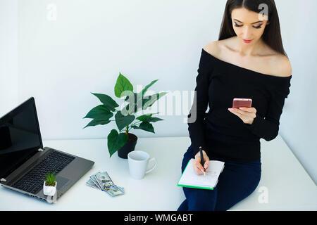 Business. Bella donna lavora in ufficio di luce mentre si tiene il computer nelle mani. Felice ragazza sorride. Alta risoluzione Foto Stock