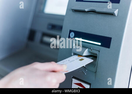 Persona inserire la scheda per automated teller machine. Incasso senza contanti dai singoli Foto Stock