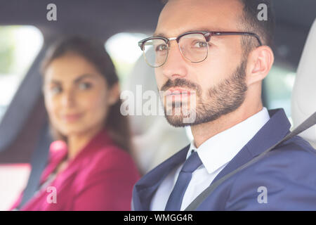 Barbuto giovane con gli occhiali seduto vicino a mia moglie in auto Foto Stock