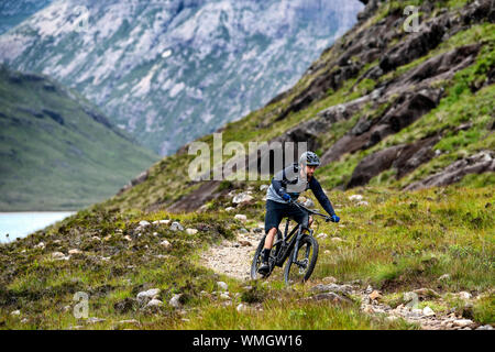 Un uomo corse in mountain bike su un sentiero tra Elgol e Sligachan sull'Isola di Skye sulla costa ovest della Scozia. Foto Stock