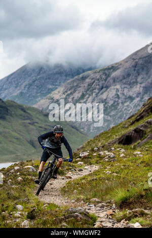 Un uomo corse in mountain bike su un sentiero tra Elgol e Sligachan sull'Isola di Skye sulla costa ovest della Scozia. Foto Stock