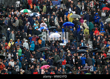 Ventole rifugiarsi sotto gli ombrelli da pioggia smette di giocare durante la giornata a due della quarta prova di ceneri a Emirates Old Trafford, Manchester. Foto Stock