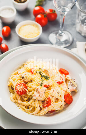 Deliziose le linguine con crema di salmone e pomodori. Spaghetti con erbe e salmone fresco Foto Stock