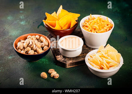 Assortimento di birra malsana spuntini: chips, nachos, pistacchi, formaggio in ciotole, vista dall'alto, copia dello spazio. Mangiare malsano concetto Foto Stock