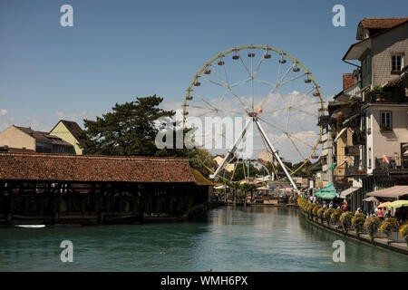 Il fiume Aare e la Obere Schleuse ponte coperto in legno di Thun, Svizzera, con l'estate ruota panoramica Ferris. Foto Stock