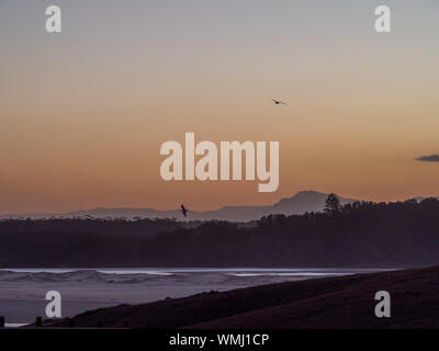 Scena del tramonto sulla spiaggia, montagne nebbiose, NSW Australia Foto Stock