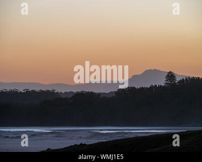 Cielo rosa e arancione al Tramonto sulla spiaggia sabbiosa e l'acqua di mare, costa Australia Foto Stock