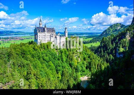 Il Castello di Neuschwanstein nel bellissimo paesaggio di montagna delle Alpi- sullo sfondo è possibile vedere il Lago di Forggensee - vicino a Füssen, Baviera, Germania Foto Stock