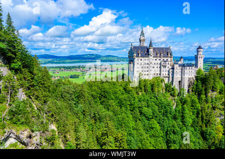 Il Castello di Neuschwanstein nel bellissimo paesaggio di montagna delle Alpi- sullo sfondo è possibile vedere il Lago di Forggensee - vicino a Füssen, Baviera, Germania Foto Stock