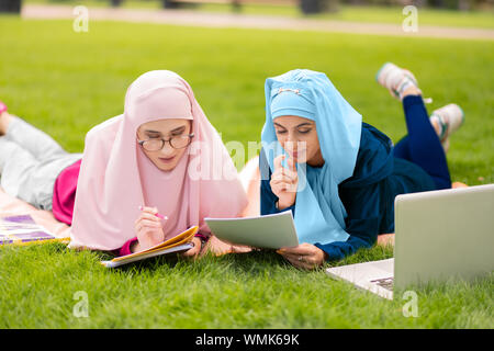 Due studenti musulmani seduti su erba e preparazione per esame Foto Stock