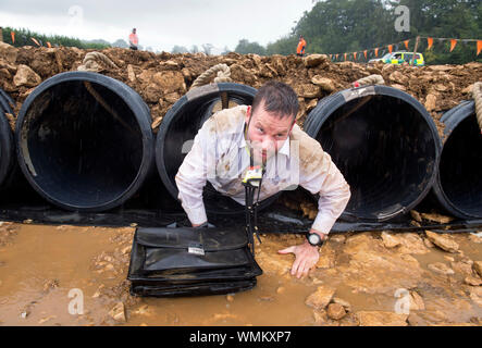 Un uomo negozia il "Kiss di fango' ostacolo al duro Mudder endurance evento nel Parco di Badminton, GLOUCESTERSHIRE REGNO UNITO Foto Stock