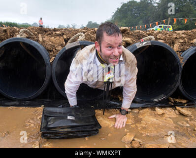 Un uomo negozia il "Kiss di fango' ostacolo al duro Mudder endurance evento nel Parco di Badminton, GLOUCESTERSHIRE REGNO UNITO Foto Stock