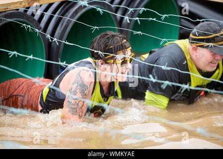 I concorrenti di negoziare la "Kiss di fango' ostacolo al duro Mudder endurance evento nel Parco di Badminton, GLOUCESTERSHIRE REGNO UNITO Foto Stock