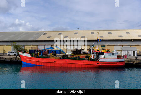 Un rosso e blu imbarcazione cargo presso la banchina di Bridgetown, Barbados Foto Stock