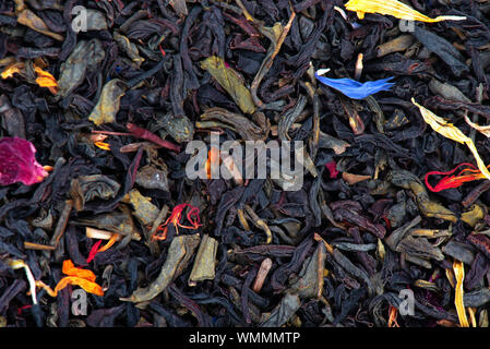 Nero e verde Ceylon Tea con fiori secchi - calendula, rose e petali di fiordaliso, sfondo. Foto Stock