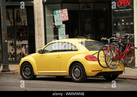 Giallo scarabeo di Volkswagen in città con le biciclette su portabicicletta Foto Stock