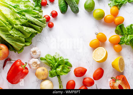 Immagine di overhead di sani ingredienti cottura sulla superficie di marmo con copia spazio. La cucina vegetariana concetto. Pomodori, insalata, basilico e peperoncino. Foto Stock